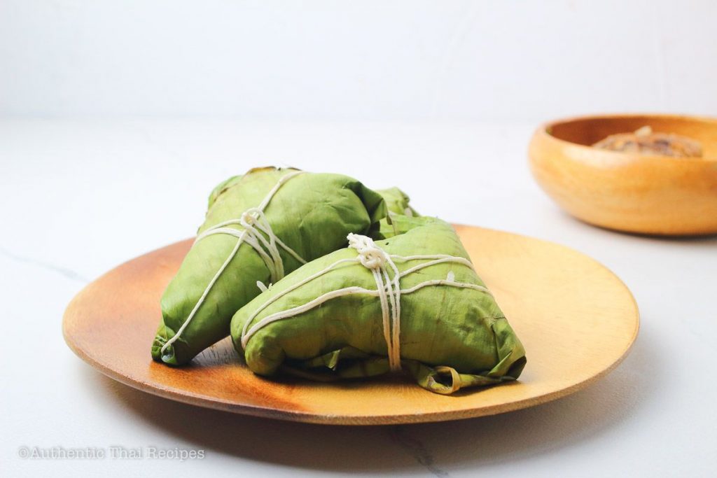 wrapped and cooked Thai sticky rice dumplings on a wooden plate