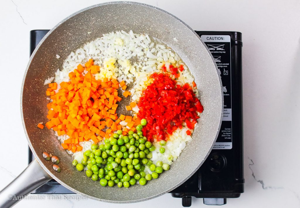 stirred in minced garlic, red bell pepper, green peas, and carrots in the pan