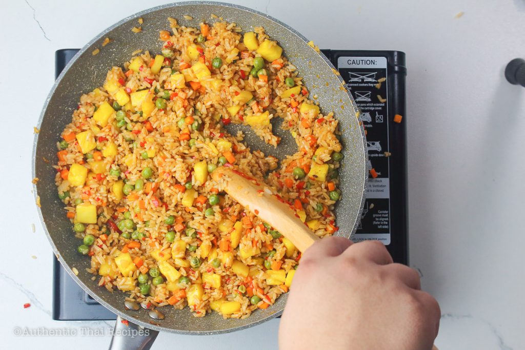 stirred pineapple Thai fried rice using a wooden ladle