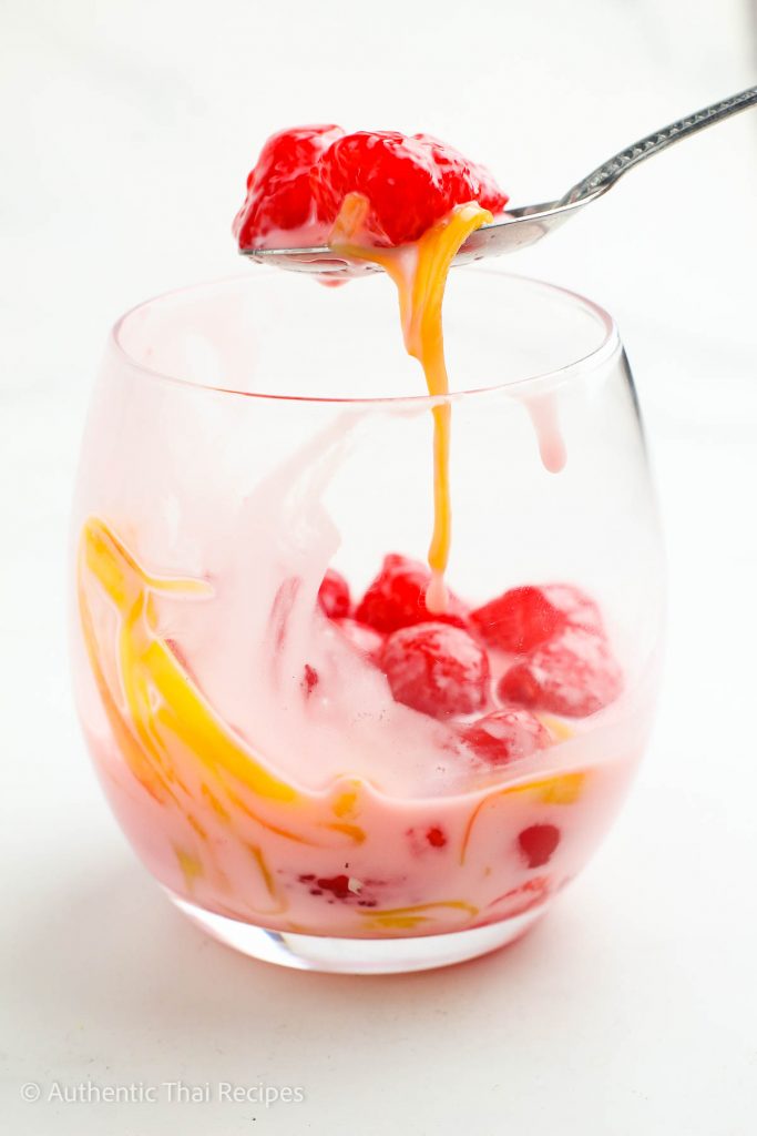 a spoon is being dipped into a bowl of thai coconut rubies dessert