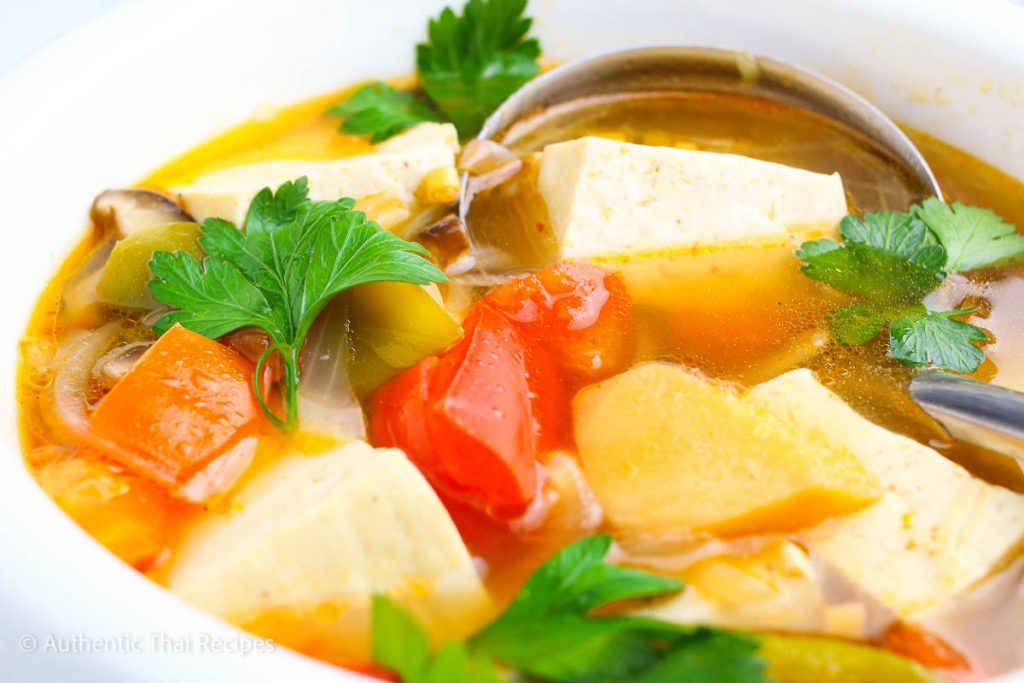 a bowl of the thai soup lemongrass garnished with cilantro with a ladle on it on a white table