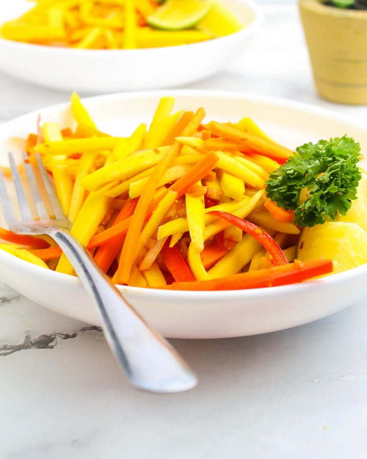 green mango thai salad garnished with cilantro on a white bowl with fork
