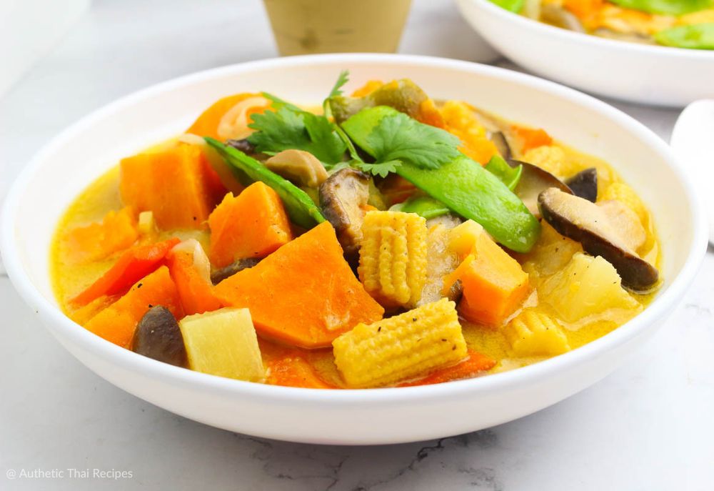 vegetable green curry in a white bowl garnished with cilantro