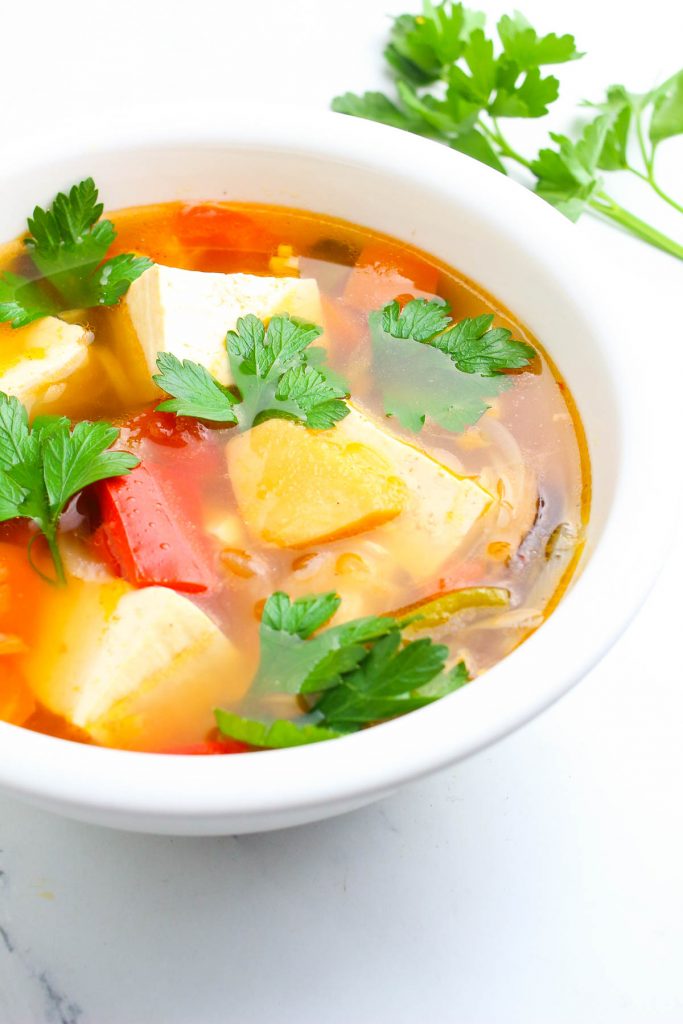 a bowl of the thai soup with lemongrass garnished with cilantro on a white table